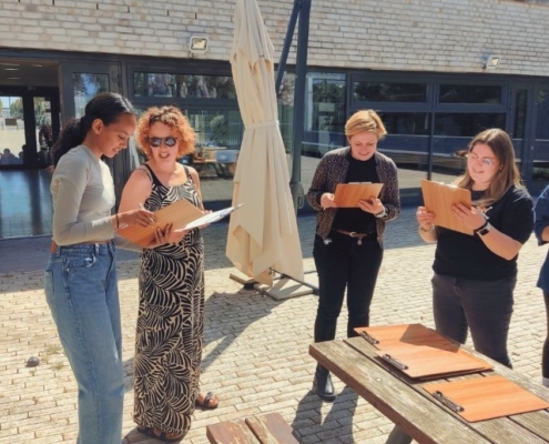 Teilnehmerinnen mit Klemmbrettern beim Feedback geben im Schreiner-Workshop