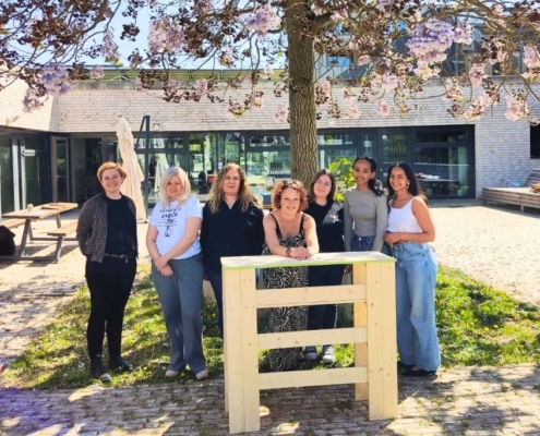 Team steht lachend hinter selbstgebautem Tresen im Schreiner-Workshop