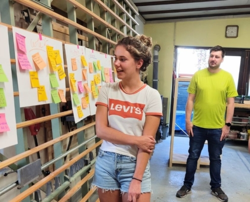 Mitarbeiterin präsentiert Ideen an Pinnwand während Team-Workshop